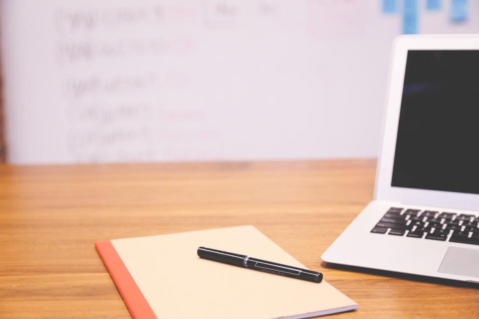 Notebook and pen beside a laptop