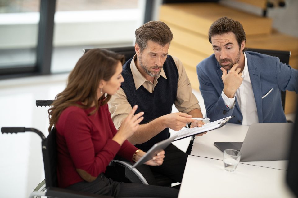 Colleagues, one in a wheelchair, discussing a document at a table