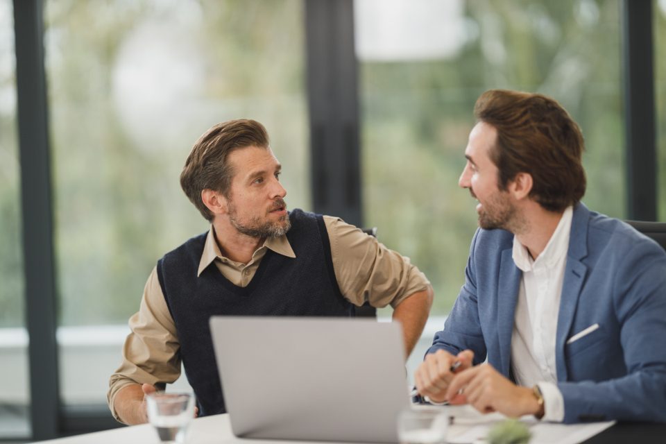 Two businessmen talking at a laptop