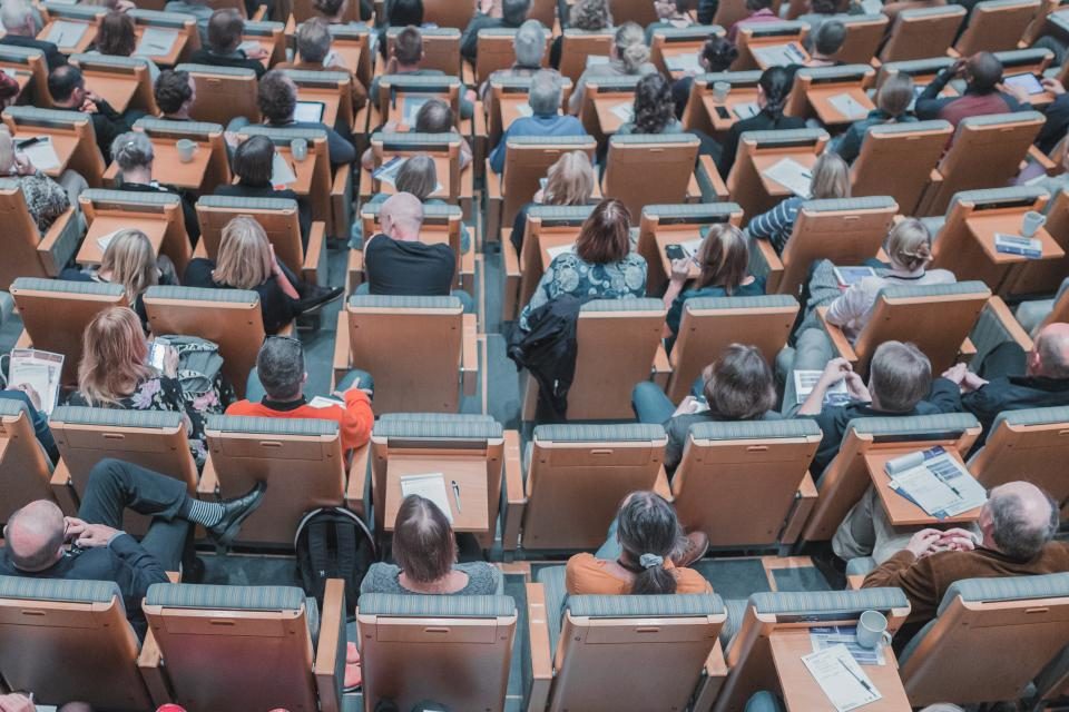 Audience seated in rows in a lecture hall, seen from above