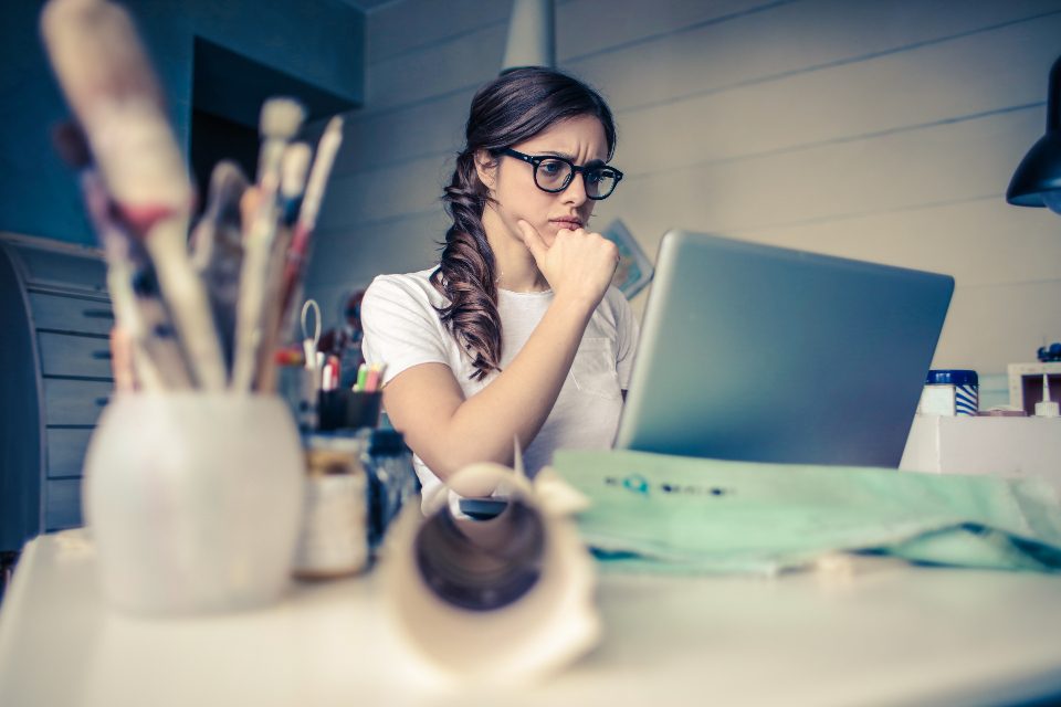 Woman thinking at her desk with a laptop