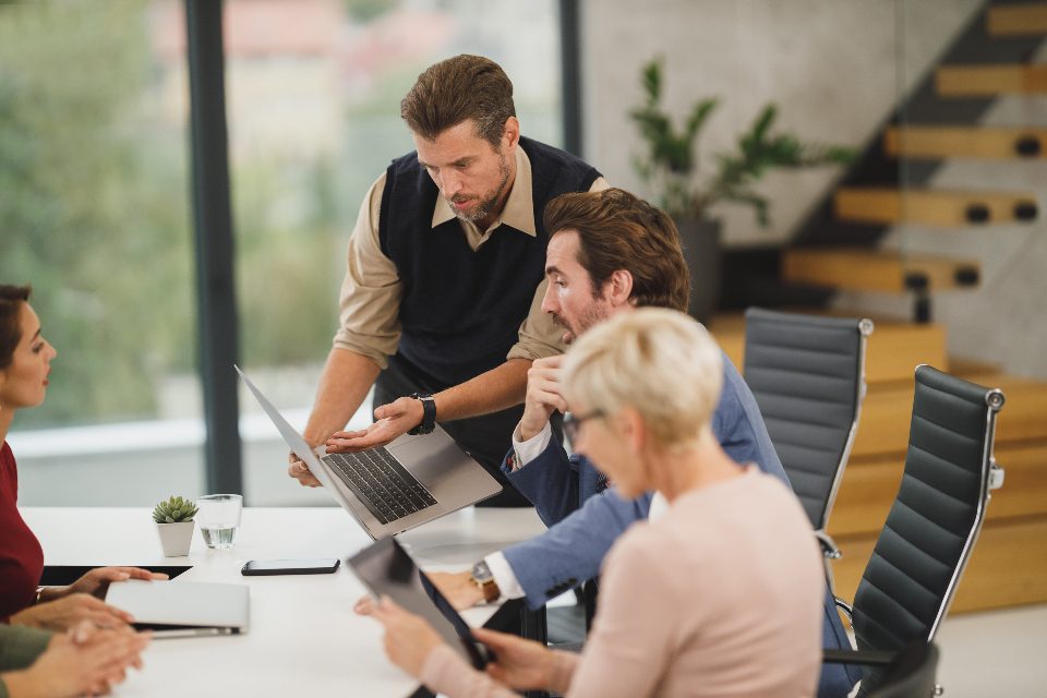 Colleagues discussing around laptops at a table