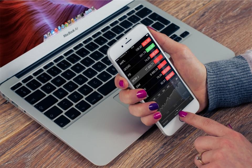 Hands holding a phone above a laptop