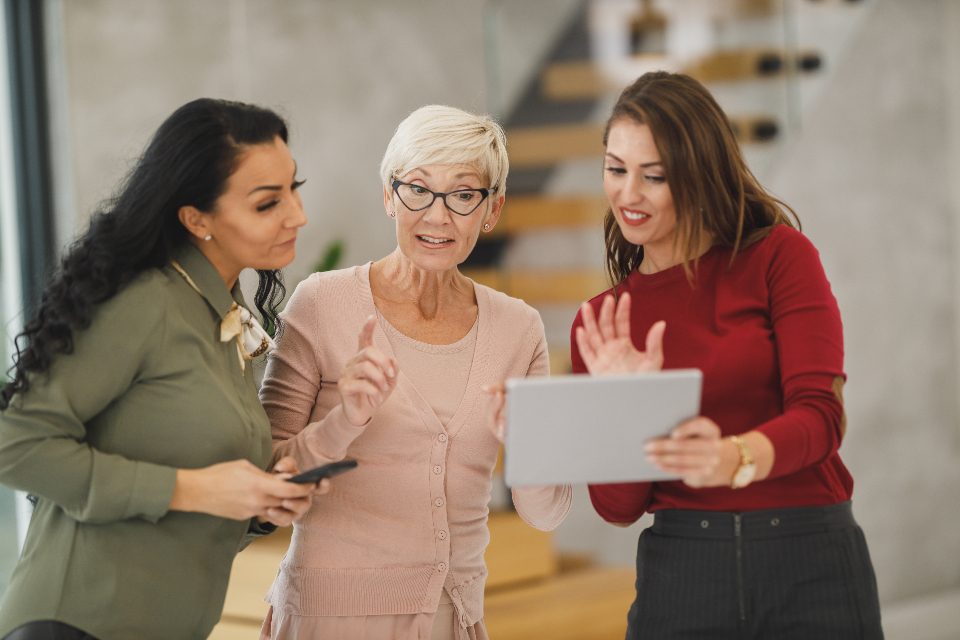 Three women looking at a tablet in an office