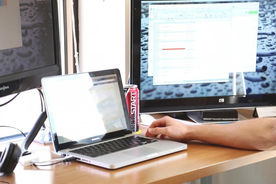 Hands using a laptop in front of a monitor
