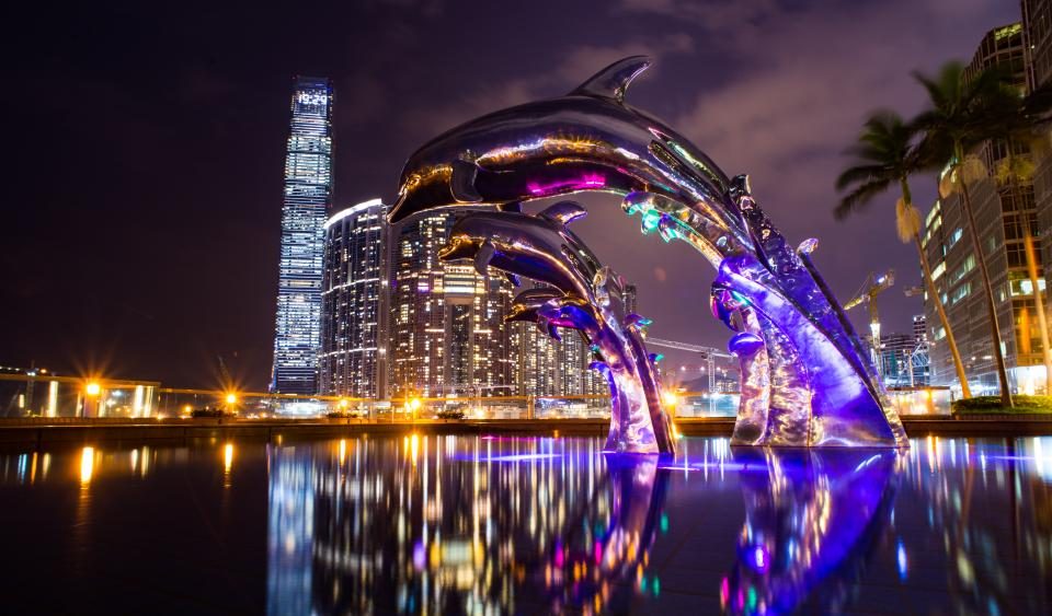 Illuminated sculpture by a city waterfront at night