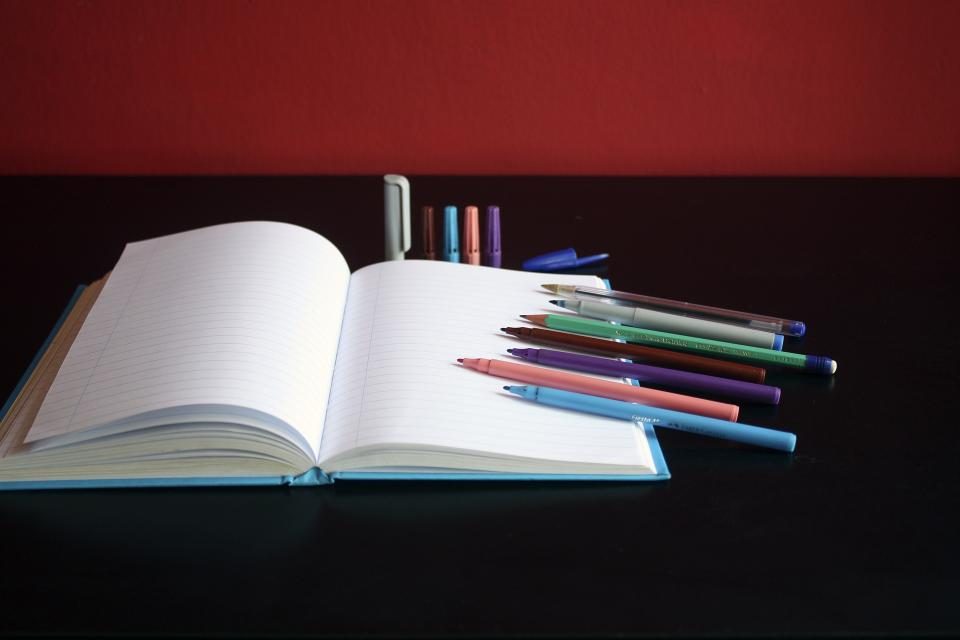 Open notebook with coloured pens