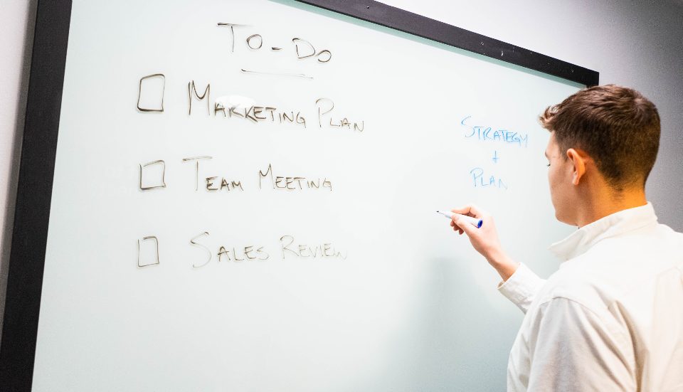 Man writing a to-do list on a whiteboard