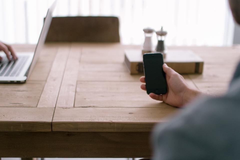 Hand holding a phone at a wooden table