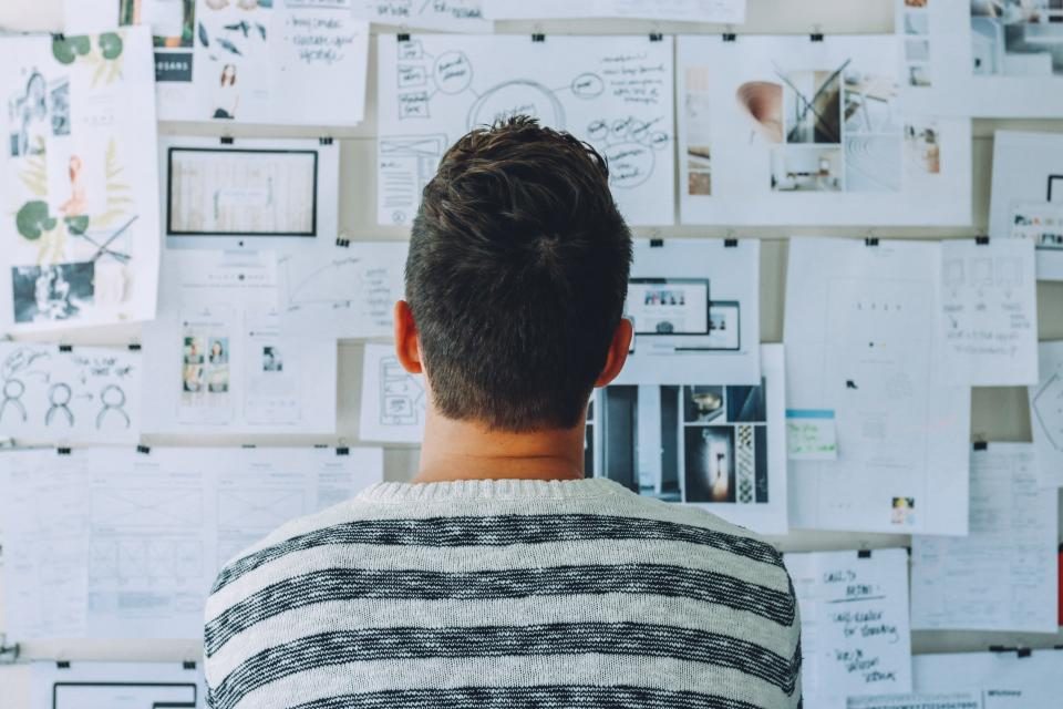 Man looking at a wall of sketches and notes