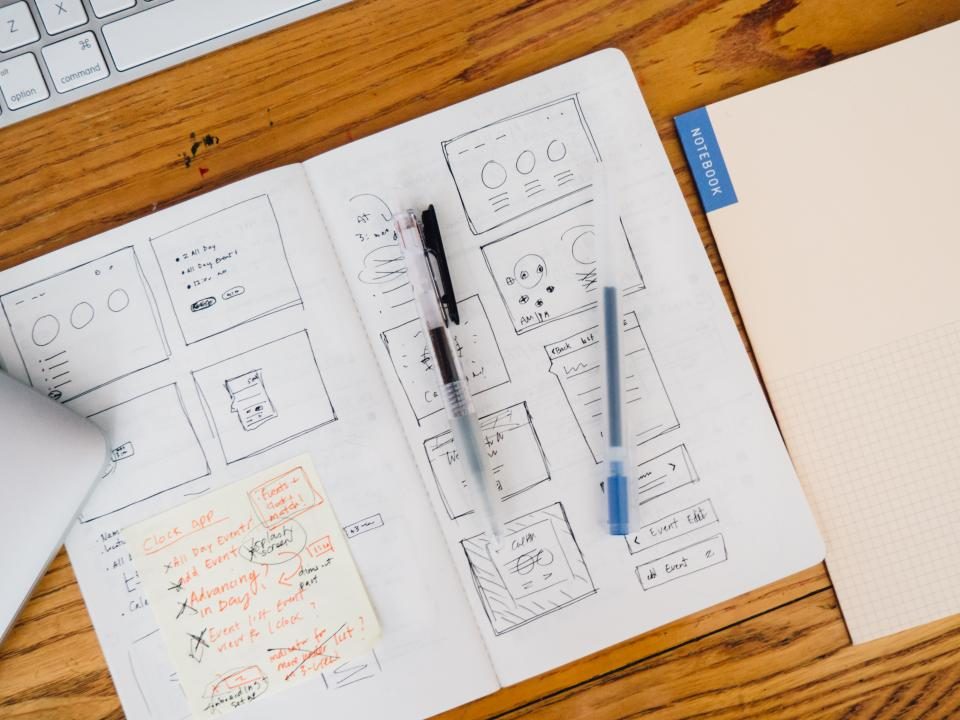 Notebook with sketches, pens and sticky notes on a desk