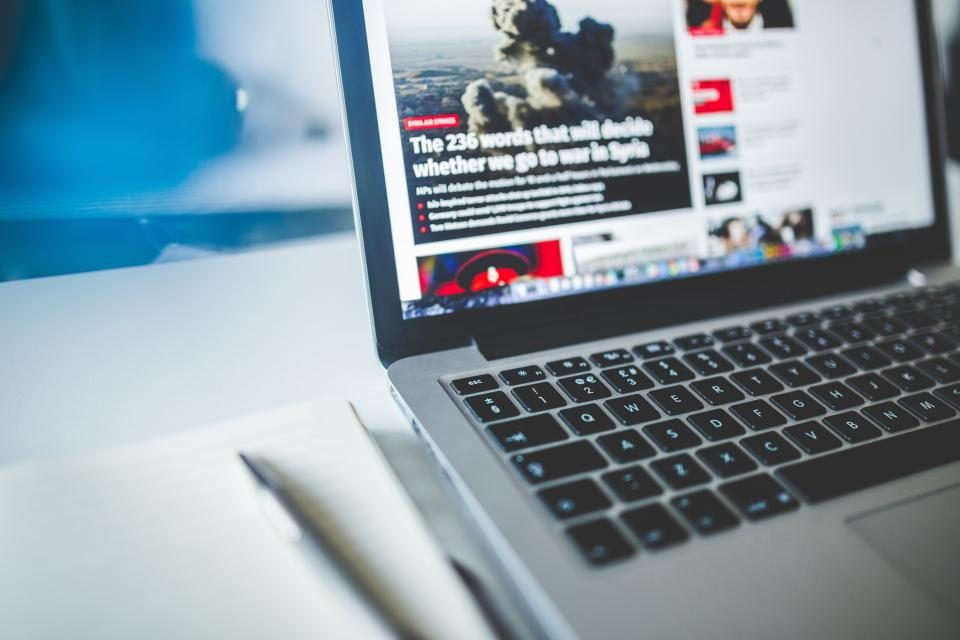 Laptop showing a news website on a desk