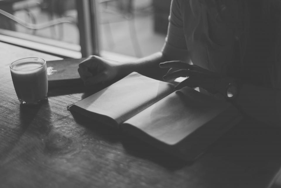 Hands with a notebook and a glass on a table