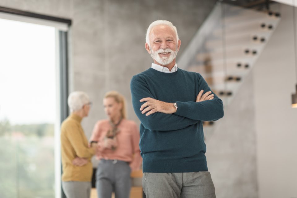 Senior manager standing in an office with colleagues behind him