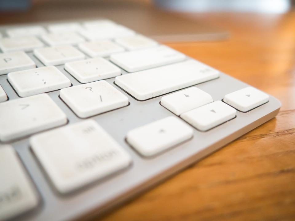 White keyboard keys on a wooden desk