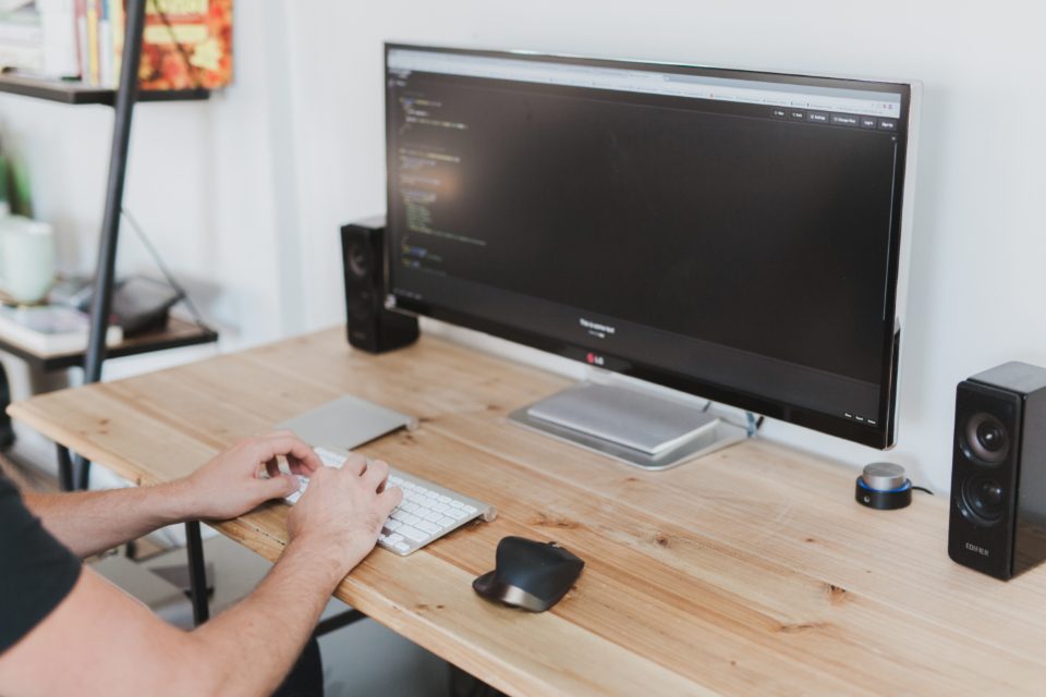 Person working at a desktop computer on a wooden desk