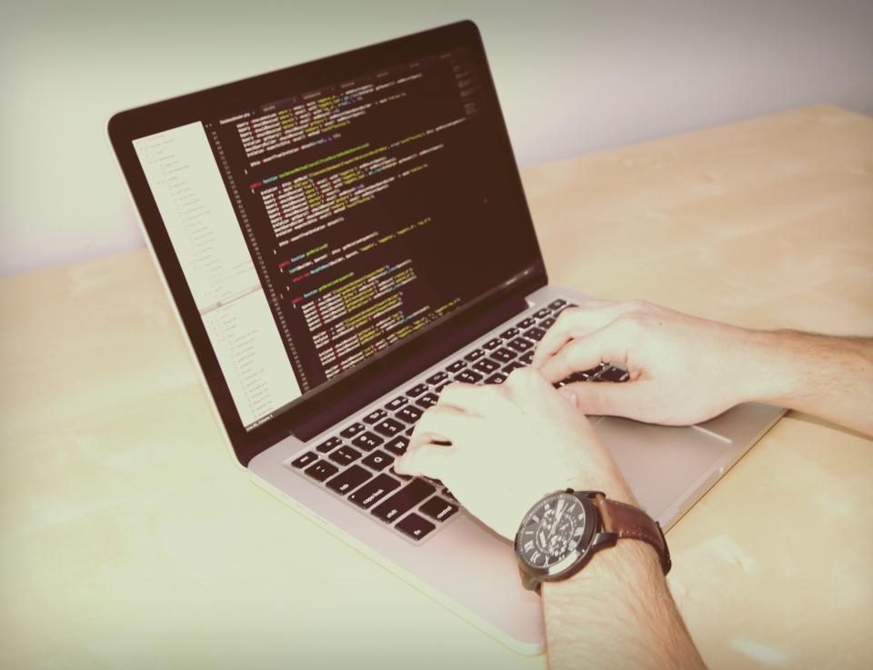 Hands typing code on a laptop