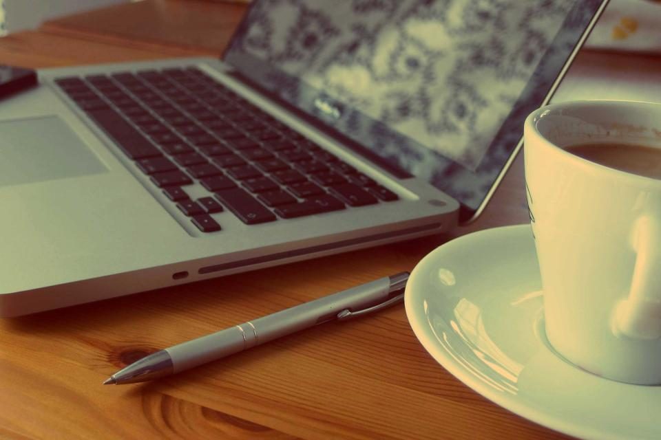 Laptop, coffee cup and pen on a desk