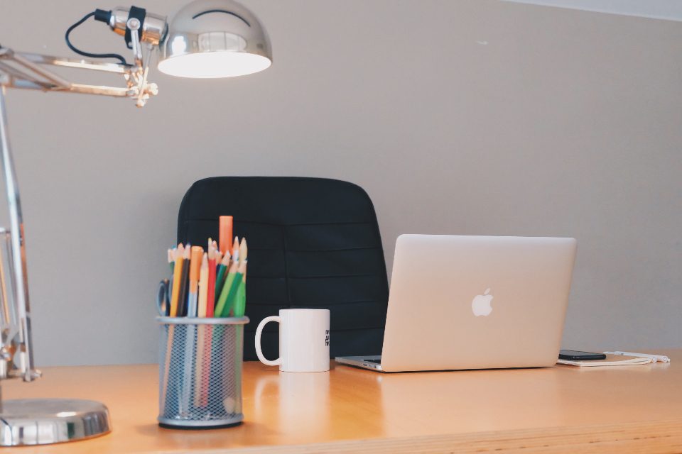 Desk with a laptop, a pencil holder and a mug