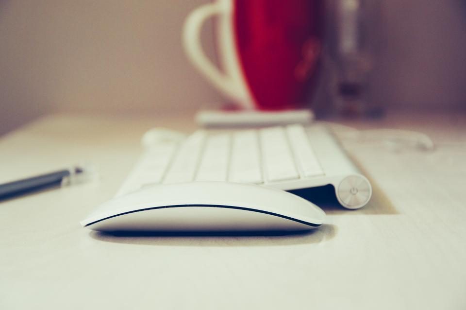 Keyboard and mouse beside a red mug