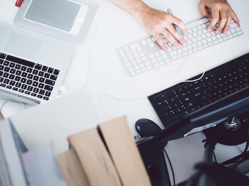 Hands typing on a keyboard beside a laptop