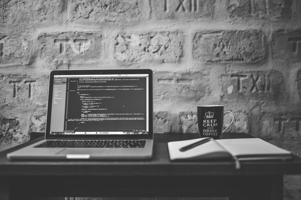 Laptop showing code against a brick wall