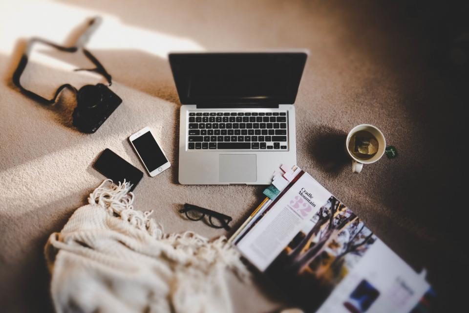 Laptop, phones and notebooks on a desk seen from above