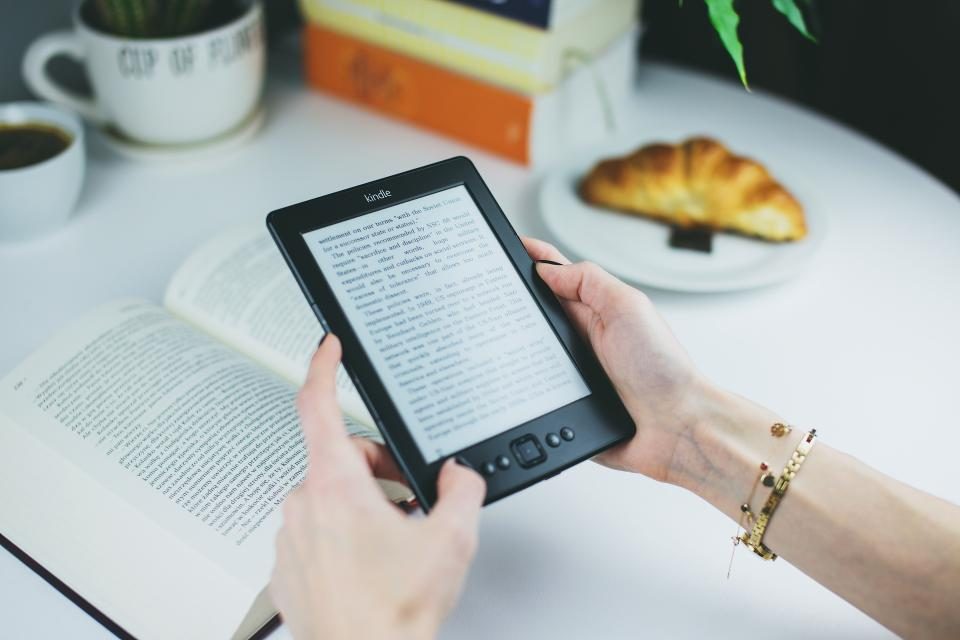 Hands holding an e-reader at a café table