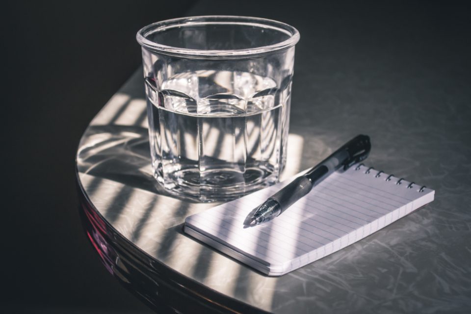 Glass of water and a notepad with a pen