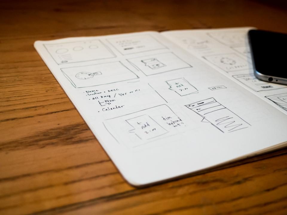 Sketches and a phone on a wooden desk