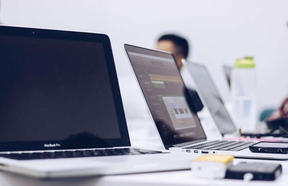 Row of laptops with people working