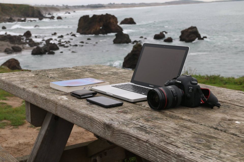 Laptop and camera on a picnic table by the sea