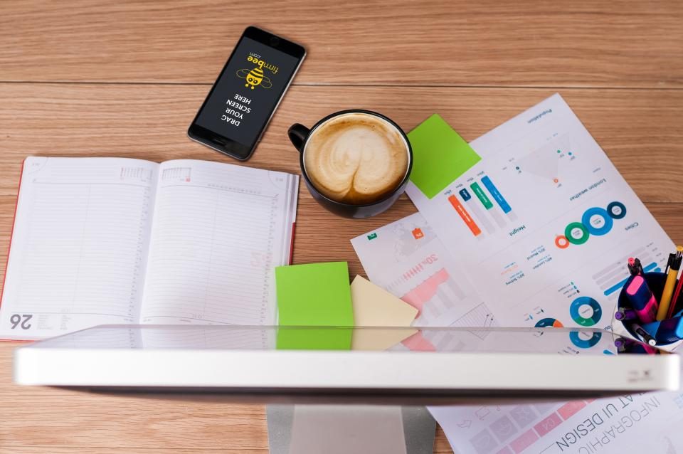 Notebook, phone, coffee and printed charts on a desk