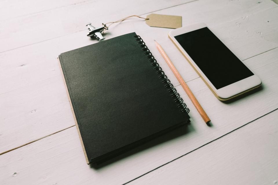 Black notebook, pencil and phone on a desk