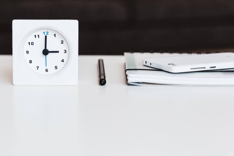 Clock on a desk beside a notebook