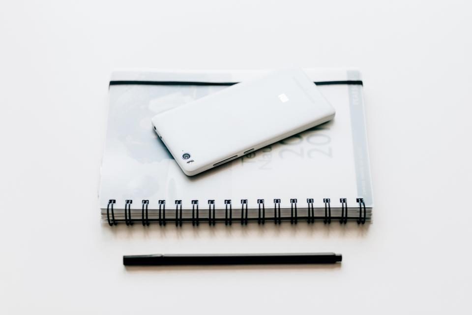 Notebook and phone on a white table